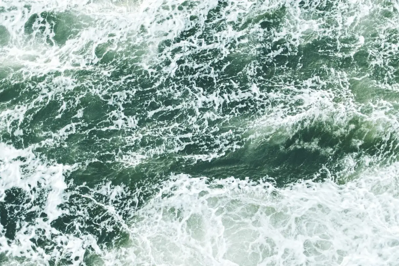 Green sea water breaking into white foam