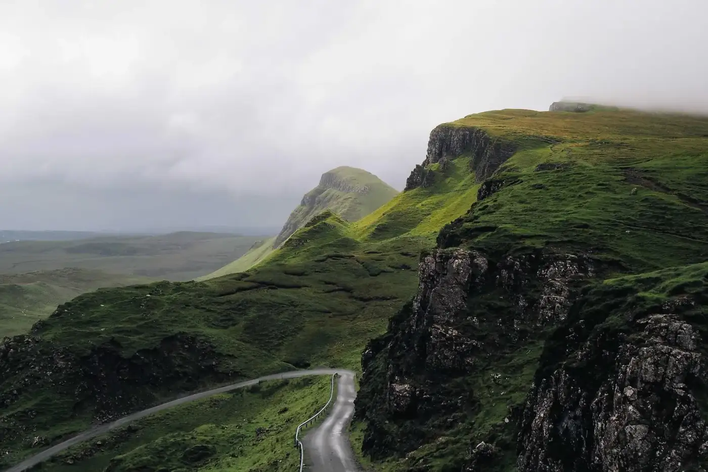 A winding road through green hills under a cloudy sky